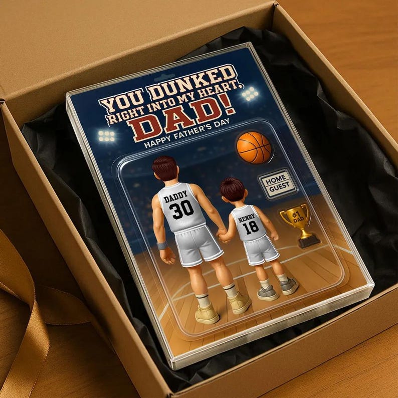 May include: A Father's Day card with a basketball theme. The card features a cartoon illustration of two basketball players, one labeled "Daddy" and the other labeled "Henry". The card has the text "You dunked right into my heart, Dad! Happy Father's Day."