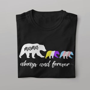 Op de afbeelding: Zwart T-shirt met een wit silhouet van een mamabeer en twee welpjes. De welpjes zijn gekleurd met de kleuren van de transgender pride-vlag. De tekst "mama always and forever" is onder de beren gedrukt.