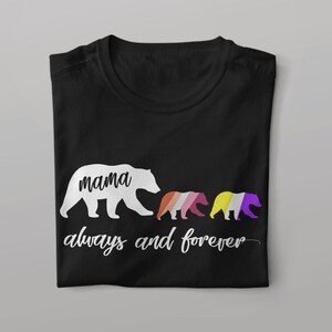 Può includere: Maglietta nera con una silhouette bianca di tre orsi. L'orso più grande dice "mamma" e gli orsi più piccoli sono colorati con i colori della bandiera del pride genderqueer. Il testo "sempre e per sempre" è scritto sotto gli orsi.