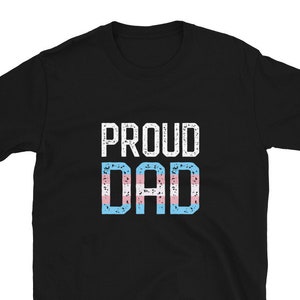 May include: Black t-shirt with the text "PROUD DAD" in white with a transgender pride flag design.