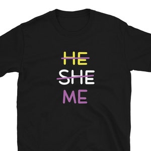 Pode incluir: Camiseta preta com as palavras "HE" riscadas, "SHE" riscadas e "ME" em letras roxas, amarelas e roxas.