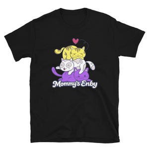 May include: Black t-shirt featuring a graphic of four cartoon cats stacked on top of each other. The top cat is yellow, the middle cat is white with black spots, and the bottom cats are purple. The text "Mommy's Enby" is below the cats.