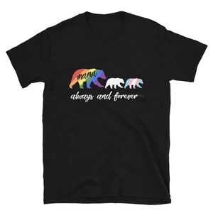 Peut inclure: T-shirt noir avec un motif de famille d'ours. L'ours maman est de couleur arc-en-ciel, l'ours du milieu est blanc et le bébé ours a les couleurs du drapeau transgenre. Les mots "mama" et "always and forever" sont également imprimés sur le t-shirt.