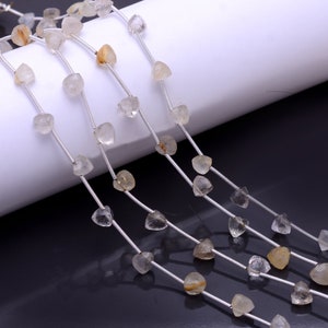 May include: Strands of raw, light-colored gemstone beads. The beads are irregularly shaped and appear to be semi-transparent, with a mix of clear and golden hues. The beads are strung on thin, silver-colored wire, creating a delicate and natural aesthetic.