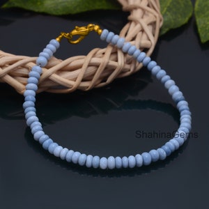 Könnte beinhalten: Ein hellblaues Opal-Perlenarmband mit einem goldenen Verschluss. Das Armband besteht aus kleinen, runden Perlen und ist etwa 18 cm lang.