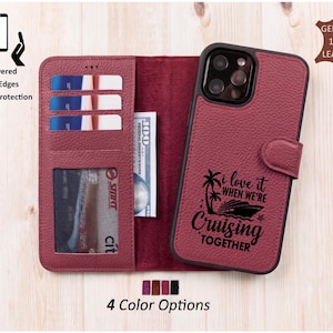 May include: A burgundy leather wallet-style phone case with a magnetic strap. The front features a black graphic of a cruise ship, palm trees, and the text I LOVE IT WHEN WE'RE CRUISING TOGETHER. The interior has three card slots and a clear ID window.