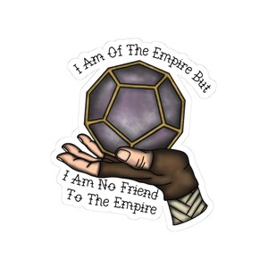 May include: A sticker showing a geometric shape in purple and gold, held in a hand with a brown sleeve. The text reads "I Am Of The Empire But I Am No Friend To The Empire."