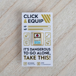 May include: Gold-coloured enamel pin featuring a card with a red X and the text "ハンターハンター" in Japanese. The card is surrounded by a blue border. The pin is on a white card with the text "CLICK & EQUIP", "IT'S DANGEROUS TO GO ALONE, TAKE THIS!" and social media handles.