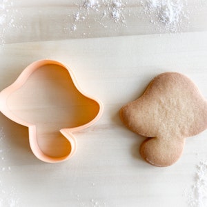 Peut inclure: Gros plan sur deux emporte-pièces, l'un en forme de champignon et l'autre rond simple. Les deux sont en plastique orange clair.