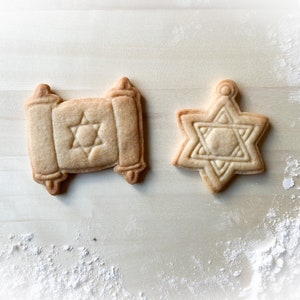 Op de afbeelding: Twee suikerkoekjes versierd met een Davidster. Een koekje is in de vorm van een rol en de andere in de vorm van een ster.