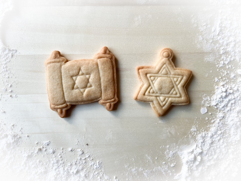 Op de afbeelding: Twee suikerkoekjes versierd met een Davidster. Een koekje is in de vorm van een rol en de andere in de vorm van een ster.