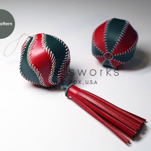 May include: Two red, green, and white leather ornaments with white stitching. The ornament on the left has a red leather tassel attached.