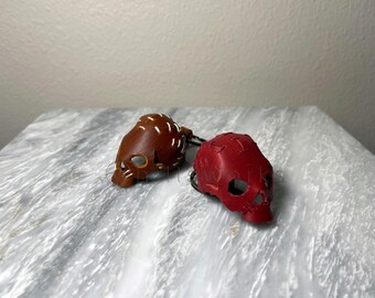 May include: Two leather skull keychains, one brown with white stitching and one red with white stitching.