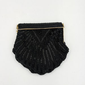 May include: A black beaded evening bag with a gold clasp. The bag is shaped like a scallop shell.