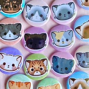 以下が含まれることがあります： 様々な毛皮のパターンと色を持つ、異なる漫画の猫を特徴とする、16個のカラフルな丸いボタンのセット。ボタンは、バッグ、ジャケット、またはその他のアクセサリーに遊び心のあるタッチを加えるのに最適です。