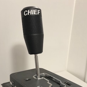 May include: Black gear shift knob with a textured surface and the word "CHIEF" printed in white on the top.
