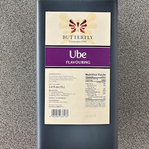 May include: A dark purple bottle of Ube flavouring with a butterfly logo and the text "BUTTERFLY Gunacipta 1948" on the label. The bottle is 1 litre (3.4 fl.oz) and is a product of Indonesia. The nutrition information is listed on the label, including 340 calories per serving.