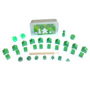 May include: A green game set with a metal tin that says "I Play Green" on the lid. The set includes dice, meeples, and a pencil.