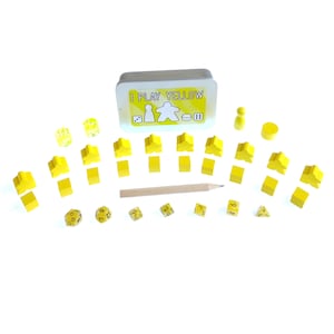 May include: A yellow game set with a tin box that says "I Play Yellow". The set includes wooden pieces, dice, and a pencil.
