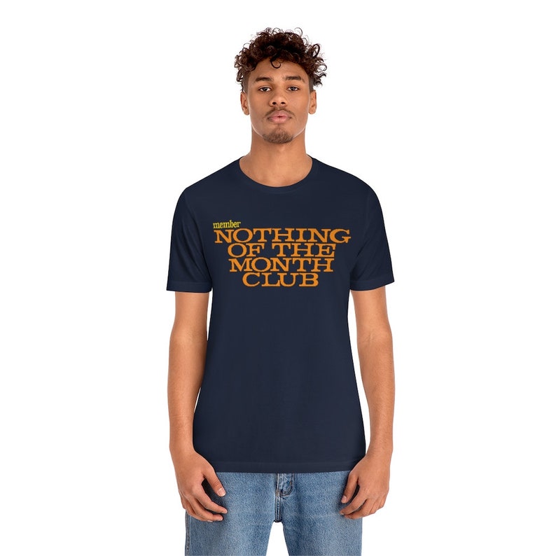 Peut inclure: Un t-shirt bleu marine avec le texte "member NOTHING OF THE MONTH CLUB" en lettres orange.