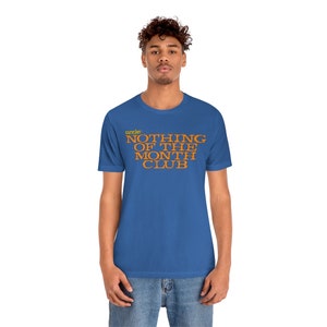 Peut inclure: Un t-shirt bleu royal avec le texte "member" en jaune et "NOTHING OF THE MONTH CLUB" en orange.