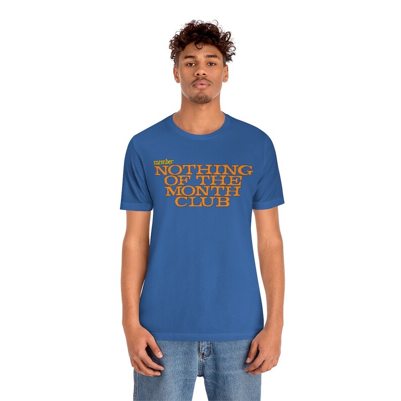 Peut inclure: Un t-shirt bleu royal avec le texte "member" en jaune et "NOTHING OF THE MONTH CLUB" en orange.