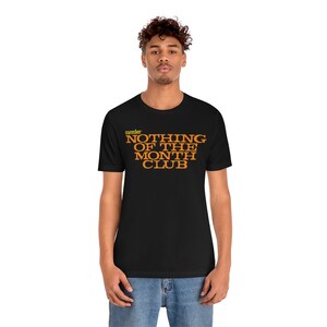 Peut inclure: Un t-shirt noir avec le texte "member NOTHING OF THE MONTH CLUB" en lettres orange.