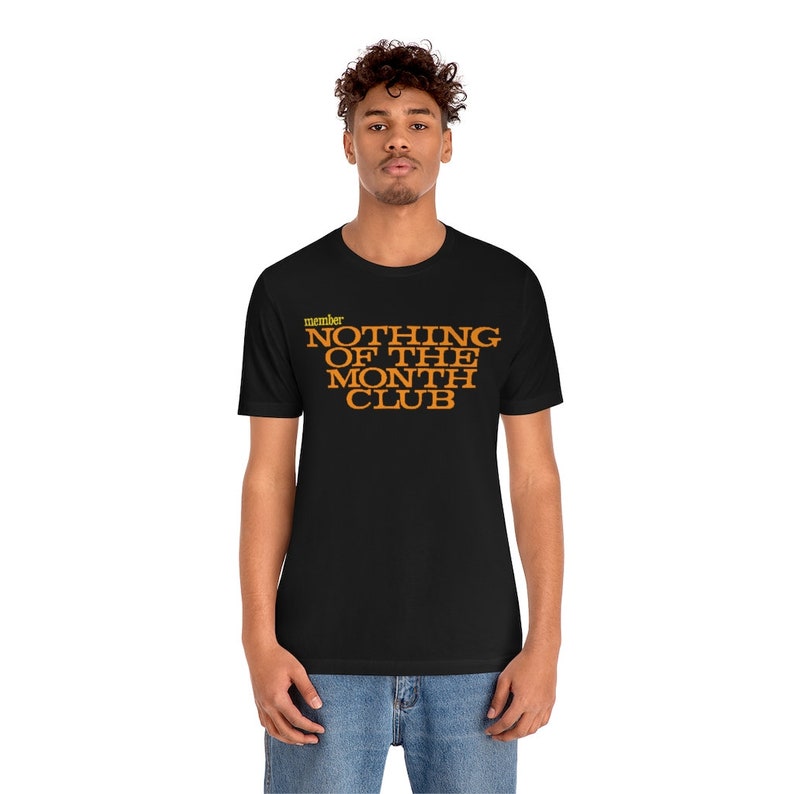 Peut inclure: Un t-shirt noir avec le texte "member NOTHING OF THE MONTH CLUB" en lettres orange.