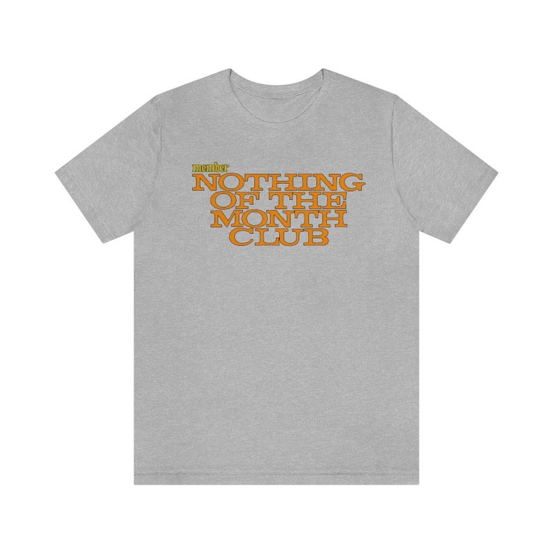 Peut inclure: Un t-shirt gris chin&eacute; avec le texte "member" en jaune et "NOTHING OF THE MONTH CLUB" en orange.