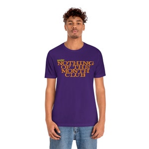 Peut inclure: T-shirt violet avec le texte "member NOTHING OF THE MONTH CLUB" en orange.