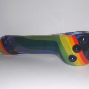 May include: A rainbow glass pipe with blue, green, yellow, orange, and red swirls. The pipe has three black glass beads on the side.