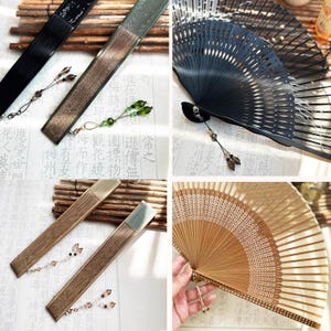 Op de afbeelding: Vier verschillende vouwvaandels met decoratieve kralenkwastjes. De vaandels zijn gemaakt van hout, bamboe en papier. De vaandels zijn in verschillende kleuren, waaronder zwart, bruin en groen.
