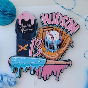May include: A baseball-themed cake topper with the name "Hudson" in pink and a baseball in a mitt. The number "13" is also featured, along with the text "Absolutely Ridiculous". The design includes blue and pink dripping accents.