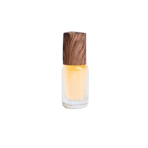 May include: A clear glass bottle with a wooden cap, filled with a light yellow liquid. The bottle is a rollerball style and is likely a perfume or essential oil.