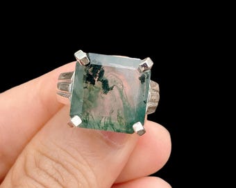 May include: A silver ring with a square green and white agate stone.