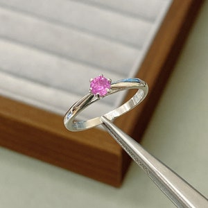 Peut inclure: Une bague en argent avec une pierre précieuse rose sertie à griffes.