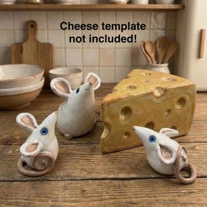 May include: Three white ceramic mouse figurines with pink-tinted ears and blue eyes, accompanied by a yellow ceramic wedge of Swiss cheese with holes. The text "Cheese template not included!" is visible above the ceramic objects.