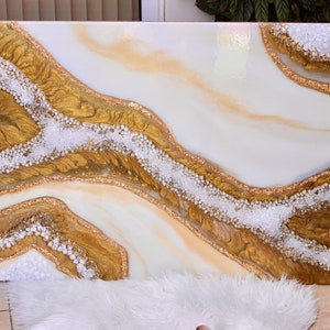 May include: Abstract art painting on canvas with white and gold flowing lines and white glitter accents.