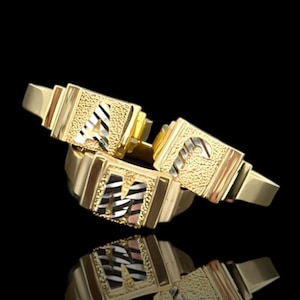 May include: Three gold rings with initial letters A, M, and C. The rings are stacked on top of each other and have a textured finish.