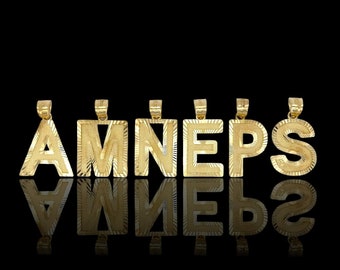 May include: Gold-plated letter pendants spelling out the word "AMNES", each letter is individually crafted and features a textured surface.
