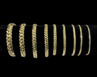 May include: Eight gold chain bracelets of varying widths and styles displayed on a black velvet background.