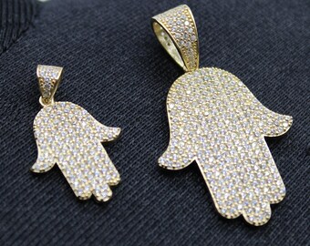 May include: Two gold hamsa hand pendants with clear cubic zirconia stones. The larger pendant is about 2 inches tall and the smaller pendant is about 1 inch tall.