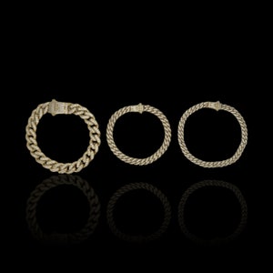 May include: Three gold chain bracelets with diamond accents. The bracelets are arranged in a row from left to right, with the largest bracelet on the left and the smallest bracelet on the right.