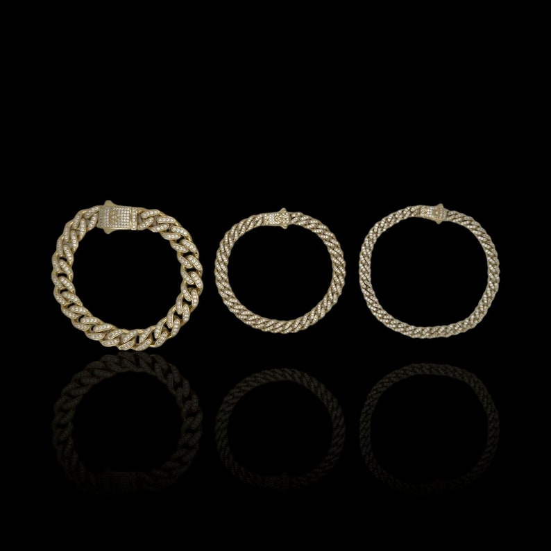 May include: Three gold chain bracelets with diamond accents. The bracelets are arranged in a row from left to right, with the largest bracelet on the left and the smallest bracelet on the right.