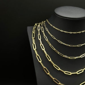 May include: A set of six gold chain necklaces of varying lengths, displayed on a black velvet stand. The chains are made of oval-shaped links.