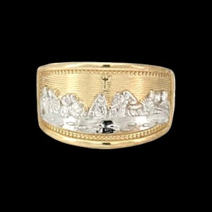 Può includere: Un anello d'oro con una raffigurazione dell'Ultima Cena in metallo bianco. L'anello è dettagliato con una croce e uno sfondo testurizzato.
