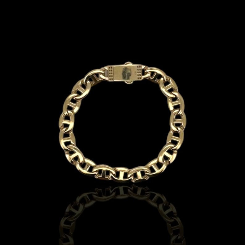 May include: A gold chain bracelet with a mariner link design. The bracelet has a clasp closure.