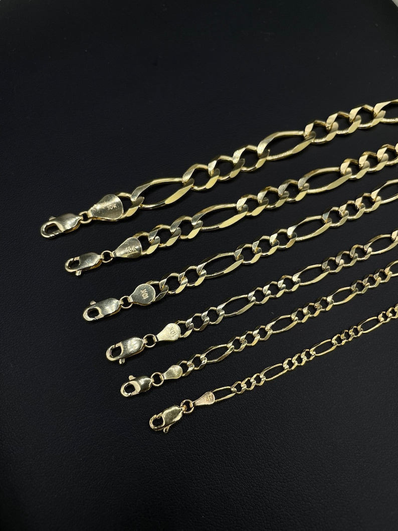 May include: A set of six gold chains with different lengths and widths. The chains are made of 10k gold and have a classic figaro design.