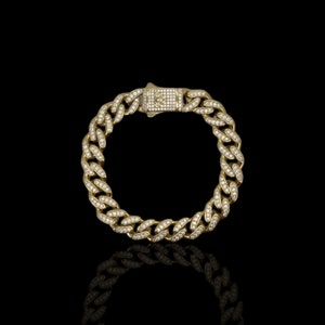 May include: A gold chain bracelet with a diamond-encrusted clasp. The chain is a thick, curb style with small diamonds set into each link.