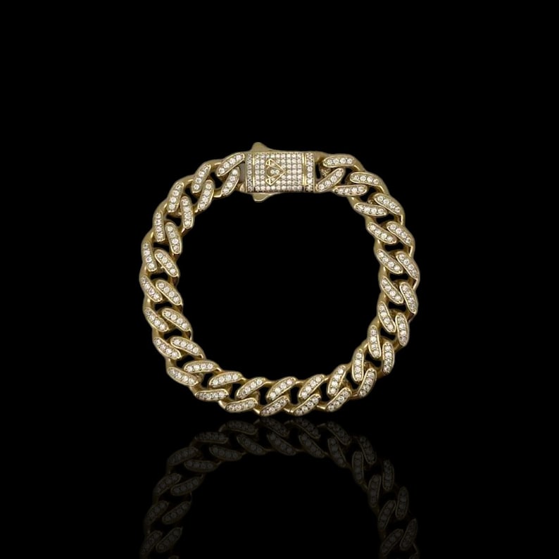 May include: A gold chain bracelet with a diamond-encrusted clasp. The chain is a thick, curb style with small diamonds set into each link.
